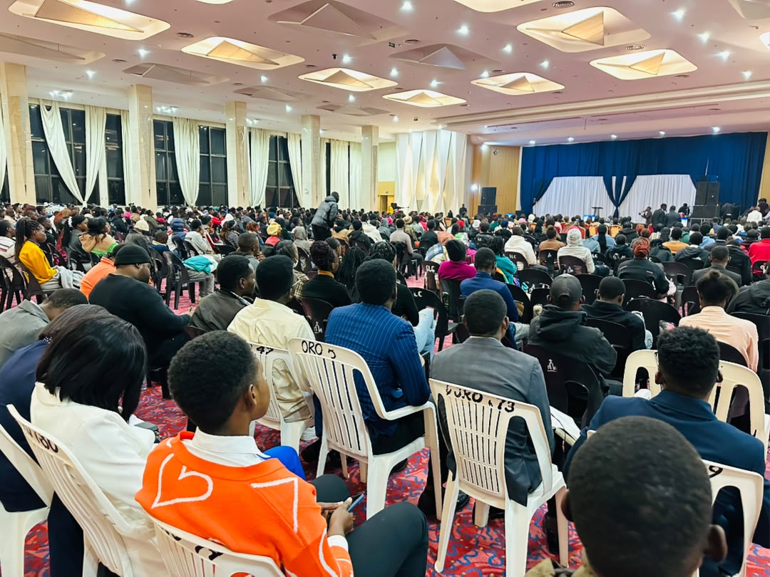Packed auditorium viewed from the back with rows of chairs